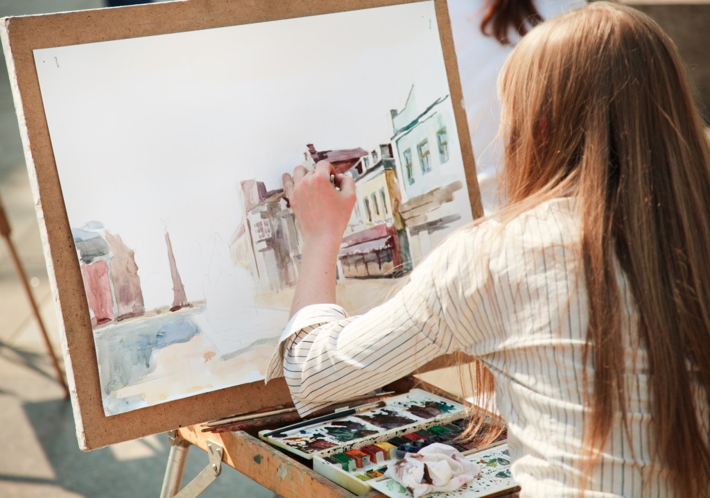 Woman painting a portrait of a city street in watercolors
