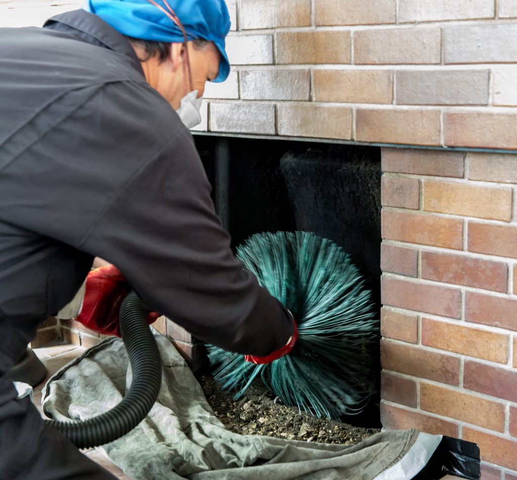 Chimney sweep wearing a mask for protection whilst cleaning chimney