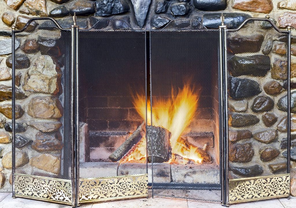 Stone fireplace in country house and fire blazing inside with natural light