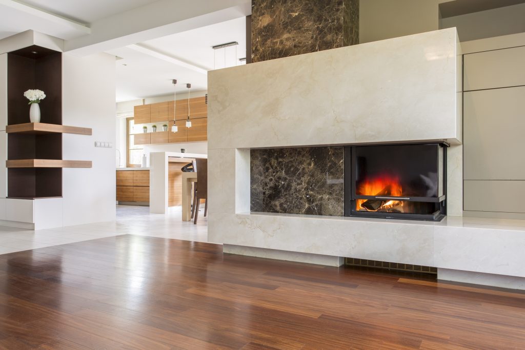 Marble fireplace in a vast living room with panelled floor, joined with bright kitchen